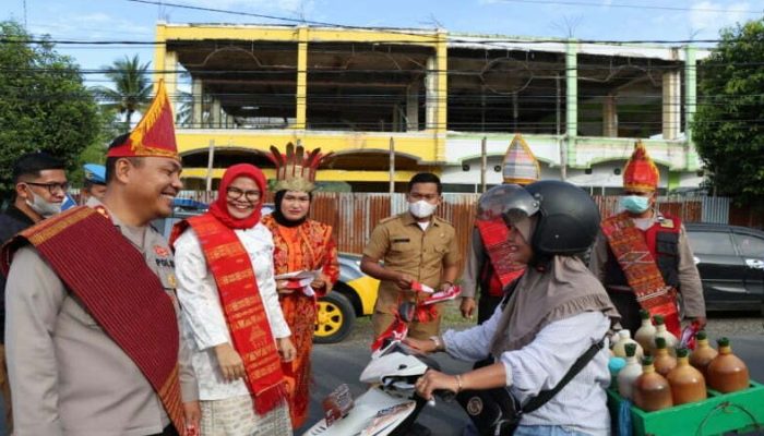 Kenakan Pakaian Adat, Kapolres bersama Pj Bupati Tapteng Bagikan 1.000 Bemdera dan Stiker